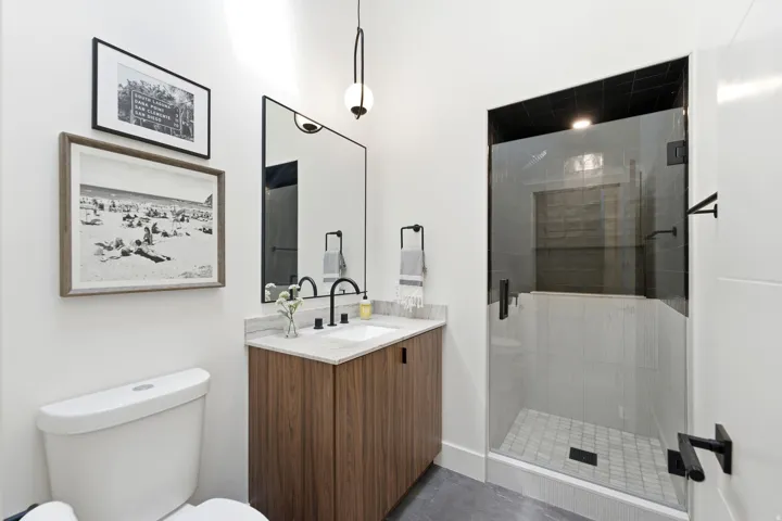 Bathroom featuring a wood-finish vanity with a light-colored countertop, an undermount sink, and a framed mirror