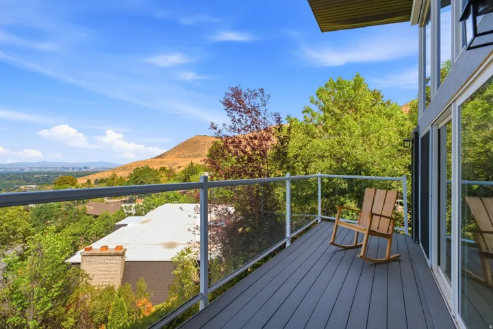Expansive outdoor deck with glass panel railing and composite decking, offering panoramic natural scenery