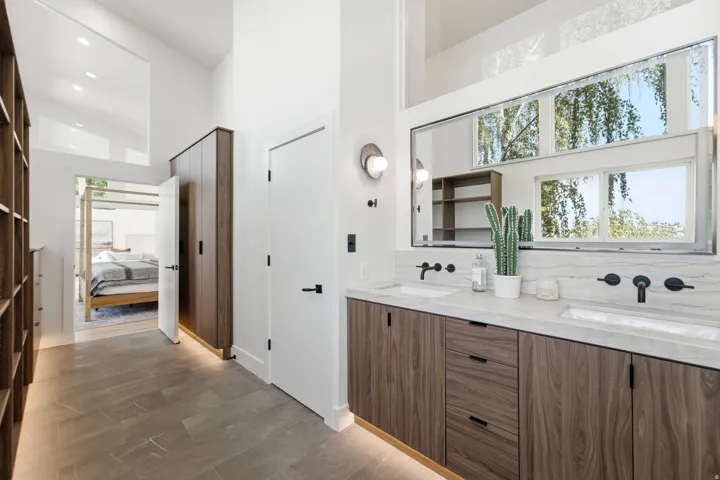 Double vanity with integrated sinks, wall-mounted matte black faucets, and wood-finish cabinetry