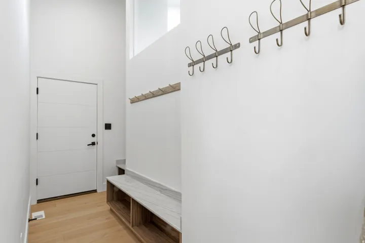 Entryway featuring a modern paneled door, light wood-finish flooring, and a built-in bench with a stone surface