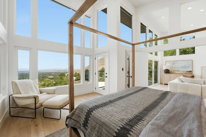 Expansive windows offering sweeping scenery, soaring vaulted ceilings, light wood-finish flooring, and a glass-paneled exterior door