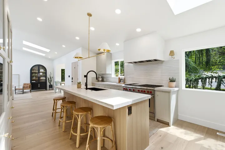Gourmet kitchen with a large central island, light wood-finish flooring, white countertops, and a professional-grade range