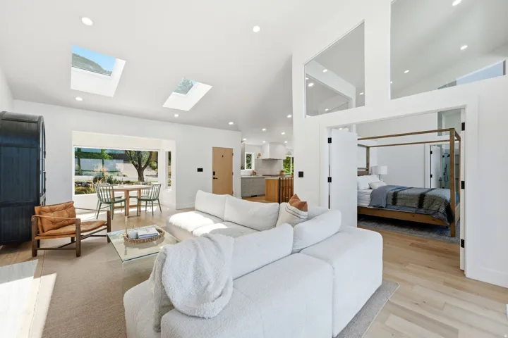 Vaulted ceilings, skylights, recessed lighting, wood-finish flooring, and a large window
