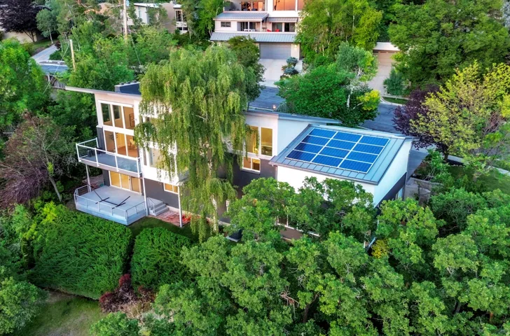 Contemporary architecture featuring multiple balconies, extensive glass panels, solar array, and mature landscaping