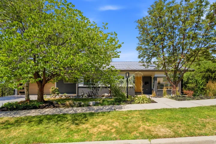 Mid-century modern exterior with a grey tile roof, contemporary light fixture, and a vibrant yellow entry door