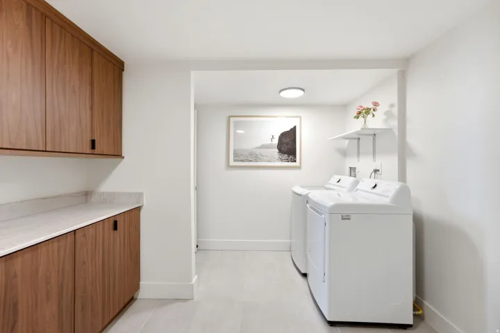 Integrated laundry area featuring wood-finish cabinetry, light-toned countertop, and recessed lighting