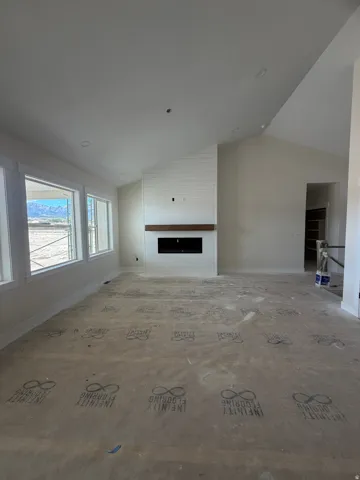 Vaulted ceiling, recessed lighting, horizontal panel accent wall, wood-finish mantel, linear fireplace