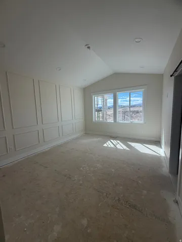 Vaulted ceiling, recessed lighting, decorative wall paneling, large windows