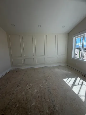 Recessed ceiling lighting, decorative wall paneling, pitched ceiling, baseboard trim