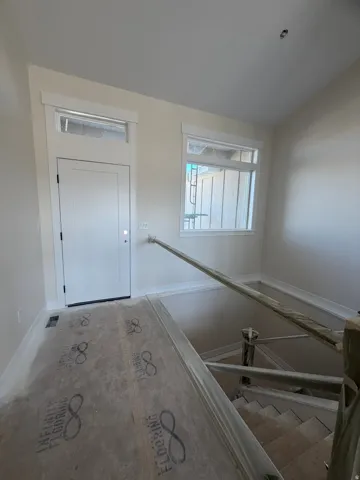 Entryway with a solid panel door, transom window, and a window for natural light