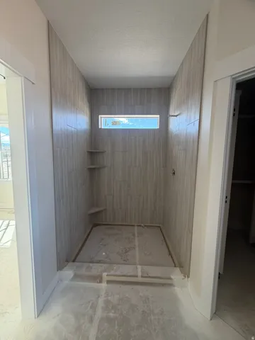 Walk-in shower with vertical tile surround, horizontal accent window, and built-in corner shelving