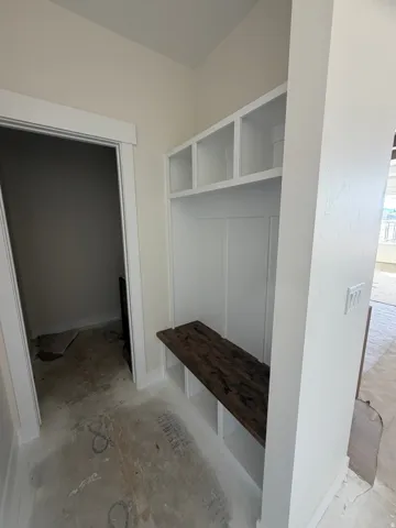 Built-in white cabinetry with a dark wood-finish bench, integrated cubbies, and overhead shelving