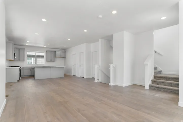 Open-concept living area with wood-finish flooring, recessed lighting, and a neutral color palette