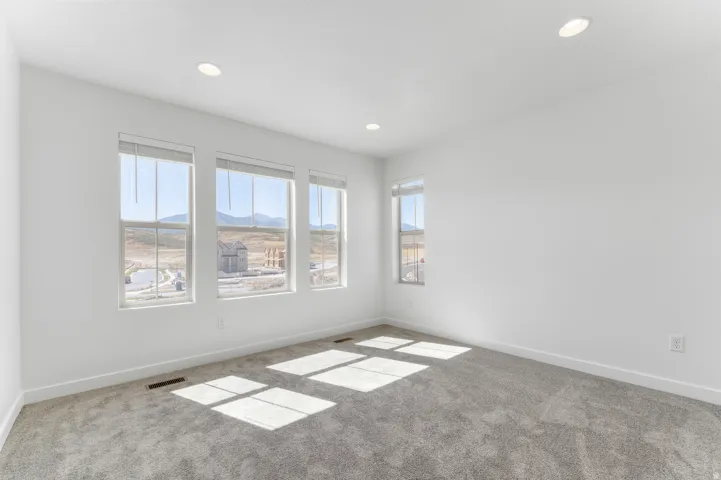 Expansive room with large windows, recessed ceiling lighting, and plush carpeting