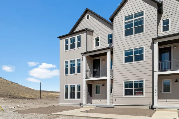Multi-story residence featuring light-toned horizontal siding and dark-trimmed windows