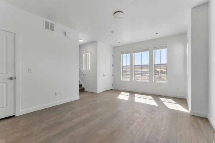 Wood-finish flooring, multiple windows, recessed lighting, and a neutral color palette