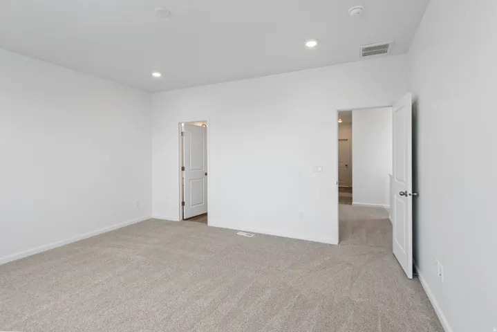 Neutral-toned carpet flooring, recessed ceiling lighting, and white interior doors