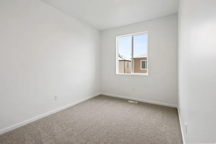 Neutral wall color, carpet flooring, and a window with a white frame