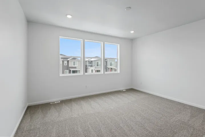 Recessed lighting, gray carpet flooring, white walls, and three white-framed windows