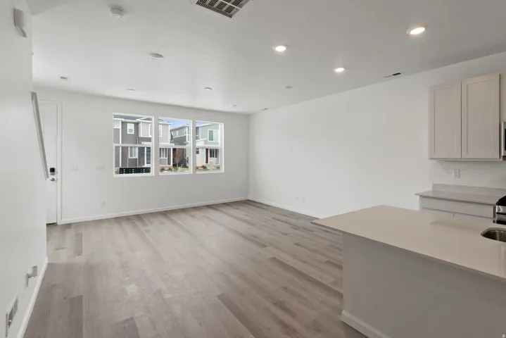 Open-concept living area featuring wood-finish flooring, recessed lighting, and multiple windows