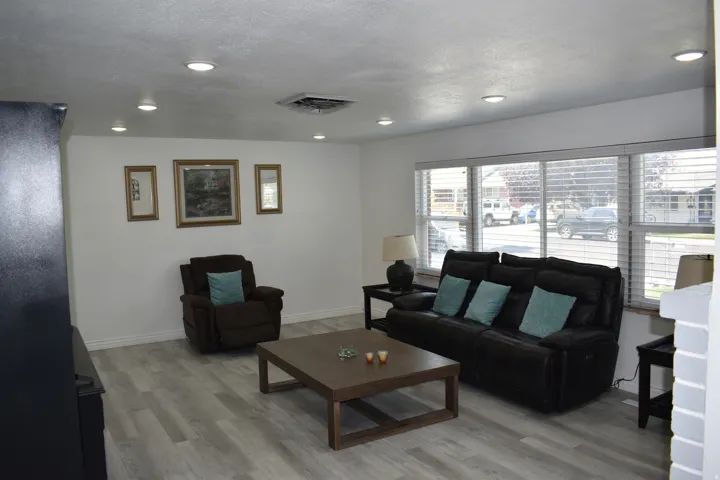 Recessed lighting throughout, wood-finish flooring, white walls, and a multi-pane window with blinds