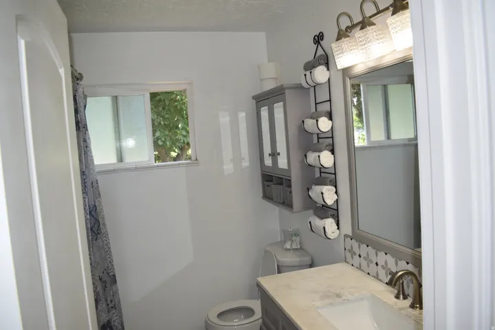 Single vanity with a light-toned countertop, under-mount sink, and bronze-toned faucet