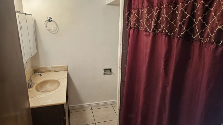 Vanity with a built-in sink and countertop, wall-mounted storage cabinet, and tiled flooring