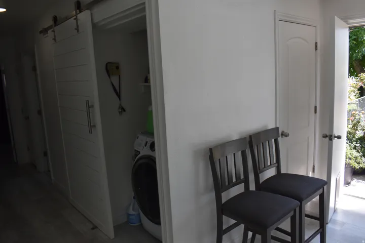 Built-in laundry area with a sliding barn door and wood-finish flooring