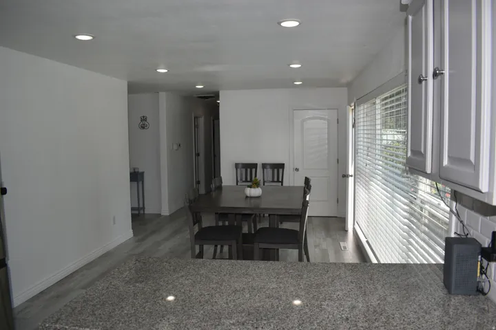 Recessed lighting, wood-finish flooring, white subway tile backsplash, light gray cabinetry with brushed nickel hardware, and granite-style countertop