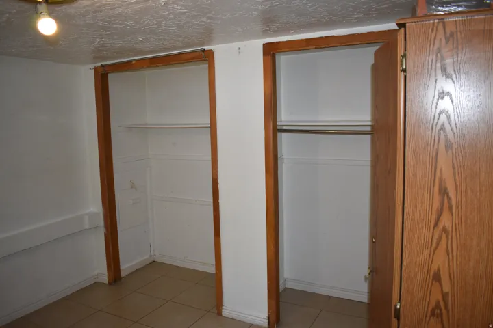 Dual closet spaces with wood-finish trim, tile flooring, and integrated shelving