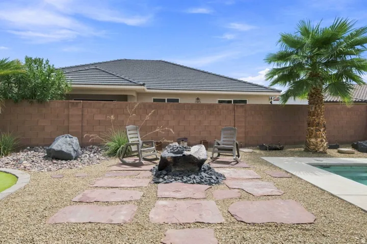 Desert-style landscaping featuring a gravel ground cover, large stepping stones, a built-in fire pit, and a swimming pool