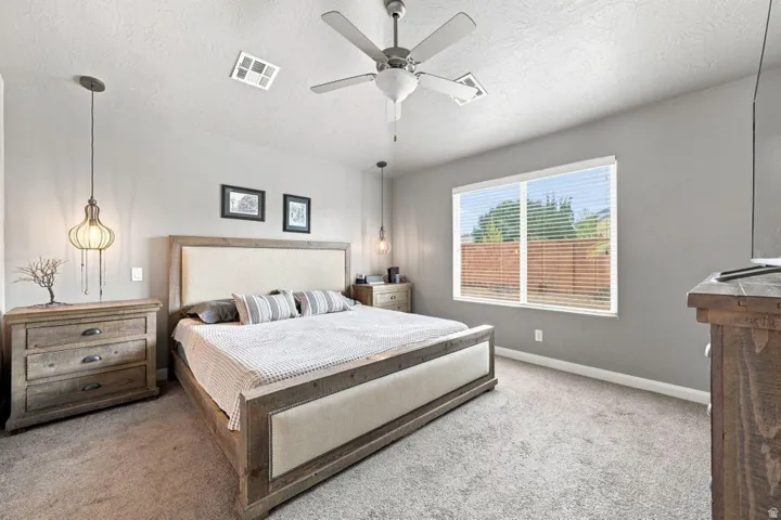 Carpeted room with a ceiling fan, dual pendant lighting, and a large window