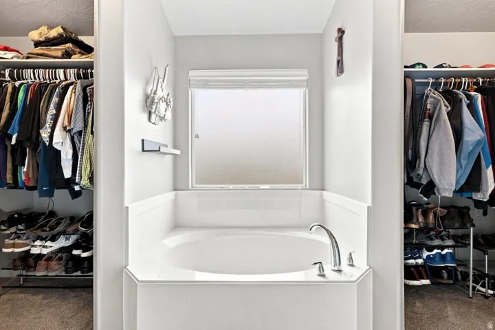 Spa-inspired soaking tub with chrome faucet and surround, framed by a large opaque window