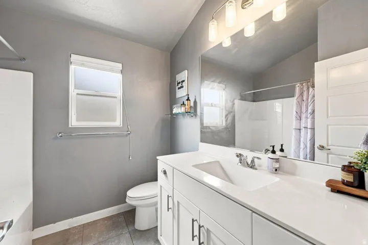 Vanity with an integrated rectangular sink, quartz countertop, and white shaker-style cabinetry