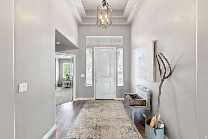 Entryway featuring wood-finish flooring, a coffered ceiling, and a prominent chandelier