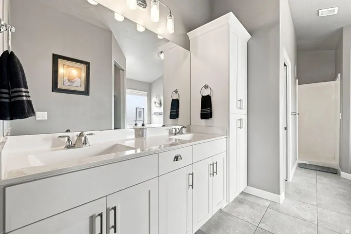 Dual vanity with integrated sinks, white cabinetry, chrome fixtures, and a separate shower enclosure