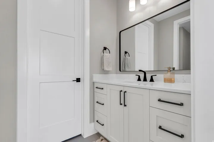 White shaker-style vanity with a light-toned countertop, integrated sink, and matte black fixtures