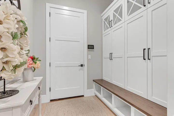White paneled doors, built-in storage cabinetry, wood-finish bench, and light wood-finish flooring