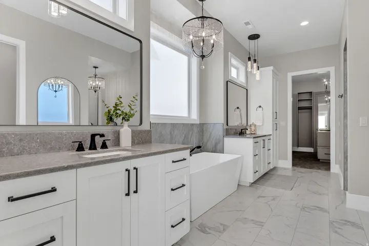 Double vanity with gray countertops, white cabinetry with black hardware, and an undermount sink