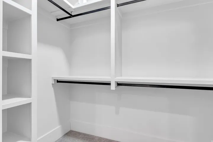 Built-in shelving, white painted walls, and black metal hanging rods