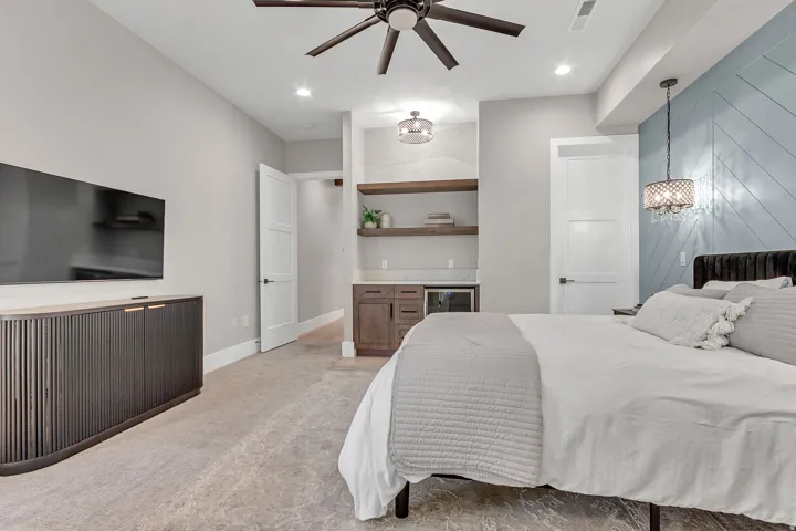 Recessed lighting, ceiling fan, built-in shelving with integrated beverage cooler, accent wall paneling, and chandelier