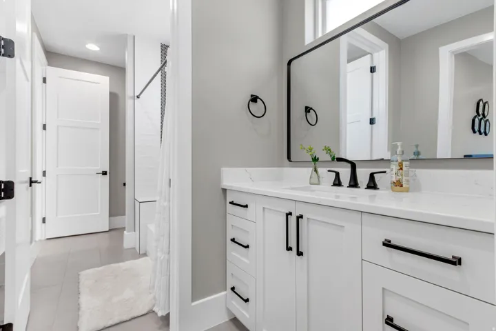 White vanity with shaker-style cabinetry, a white countertop, and a rectangular undermount sink with a matte black faucet