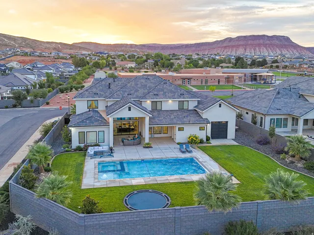 Expansive backyard featuring a large swimming pool, integrated spa, and surrounding hardscaping