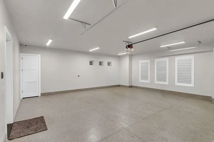 Spacious garage with an epoxy floor finish, multiple fluorescent light fixtures, and three transom windows