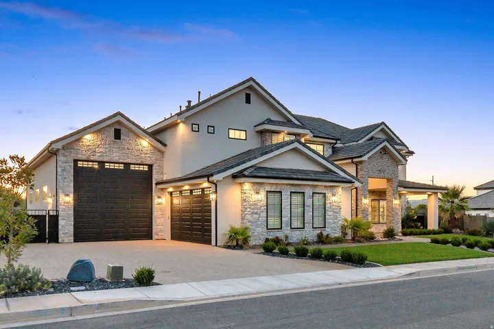 Stucco exterior with stone accents, a multi-gabled roof, and a three-car garage