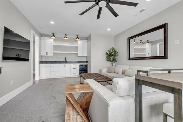 Entertainment space featuring a ceiling fan, recessed lighting, and a wet bar with white cabinetry, a dark countertop, and a beverage refrigerator
