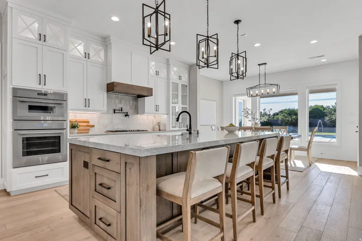 Chef's kitchen featuring a spacious island with seating, stainless steel double ovens, and white upper cabinetry