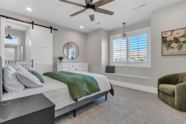 Recessed lighting, ceiling fan with integrated light, window with white plantation shutters, built-in window bench, and a barn door entry to an adjacent space