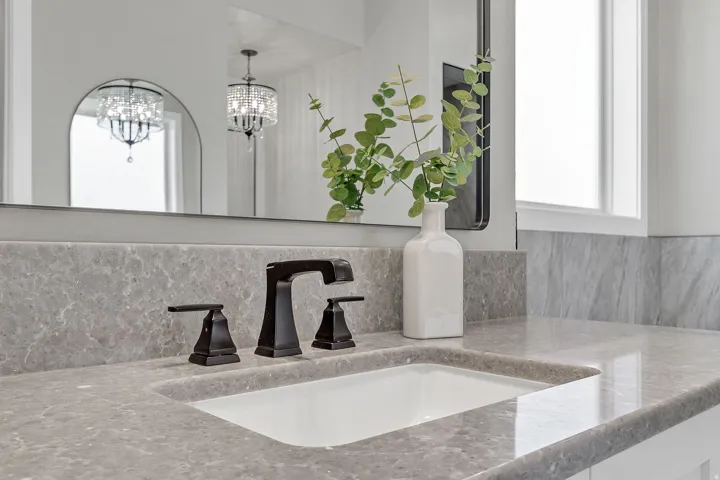 Integrated sink with a dark bronze widespread faucet, set into a gray stone countertop