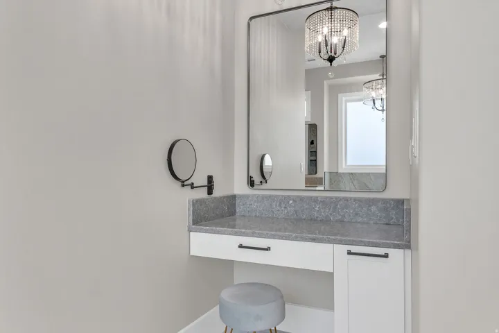 Vanity area featuring a large framed mirror, built-in cabinetry with dark hardware, and a stone countertop
